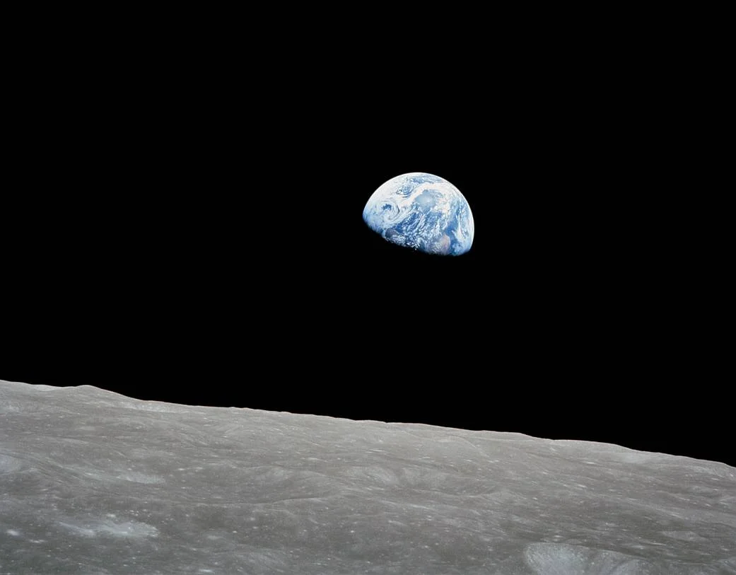 La Terre bleue et blanche dans le noir de l’espace, au-dessus de la surface grise de la Lune.